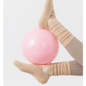 A woman wearing ballet yoga stockings is practicing with a yoga ball.